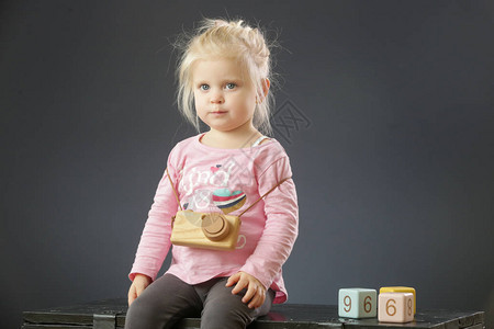 两岁小孩女穿粉红色衬衫配有木制相机玩图片
