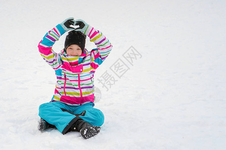 一个穿着鲜艳夹克色彩鲜艳的滑雪套头衫的女孩坐在幸福中图片