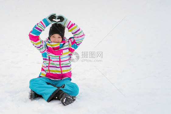 一个穿着鲜艳夹克色彩鲜艳的滑雪套头衫的女孩坐在幸福中图片