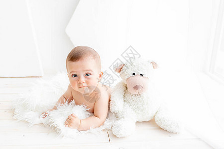 6个月的女童与一只大软熊坐在一个盛着尿布图片