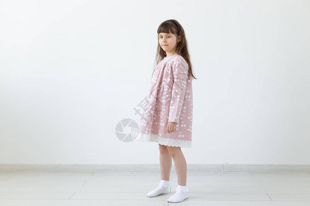 穿着粉红色连衣裙的骄傲的黑发小女孩站在白色背景上时尚童装和学龄前儿童的概背景图片