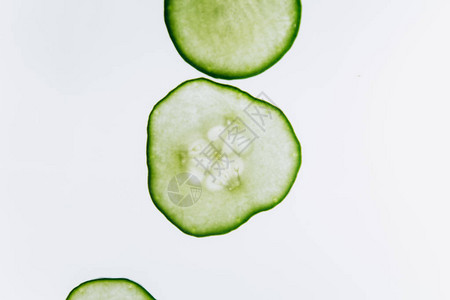 明亮的白光特写背景上的绿色半透明黄瓜片透明的蔬菜盘宏观中万花图片
