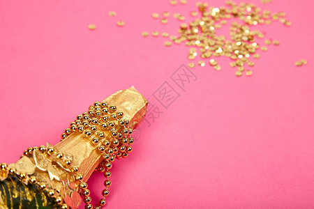 香槟瓶与粉红色纸上的金色五彩纸屑情人节生日婚礼圣诞节庆祝节日概念顶视图平背景图片