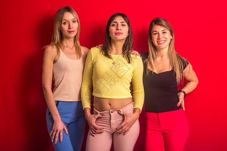 三个女孩站在红墙前和一个手放在裤子上图片