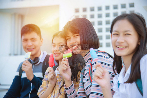 美丽的亚洲少女和朋友一起坐着吃冰淇淋与图片