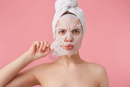 一个皱着眉头的年轻女子在淋浴后头上戴着毛巾图片