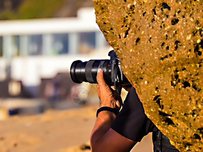 摄影师的手和照相机拍到从岩石后面拍图片