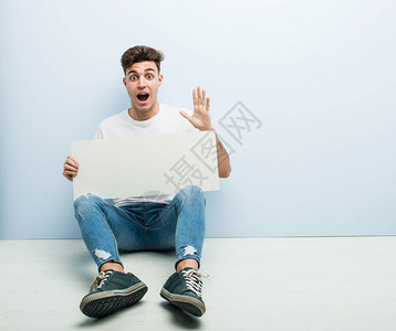 年轻人拿着标语牌坐在他家的地板上庆图片