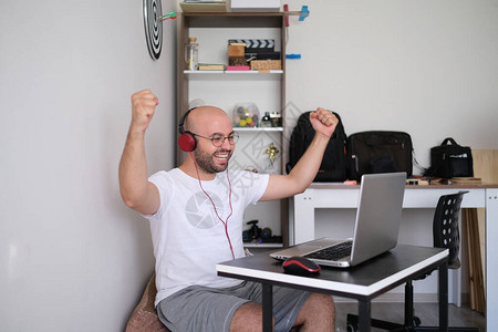 在电脑上取得成功的年轻人欢欣鼓舞地庆祝他图片