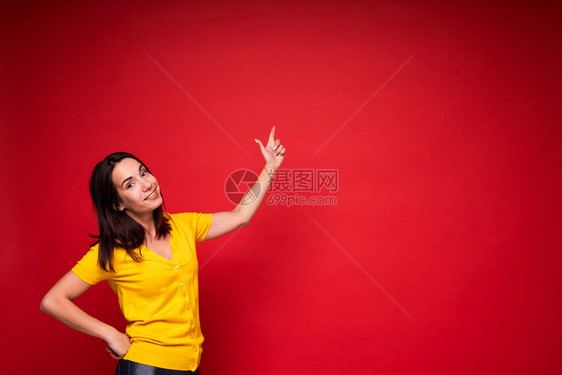 快乐的年轻成功女子用红背景将手指向图片