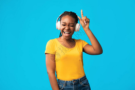 听音乐在线快乐的黑人女孩在无线耳语中歌唱在工作室享受最喜爱图片