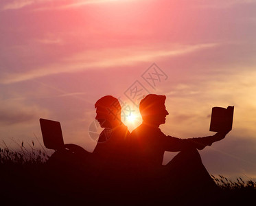 一个男人带着笔记本电脑和一本关于日落或日出背景的书剪影新旧价值观矛盾的观念旧图片