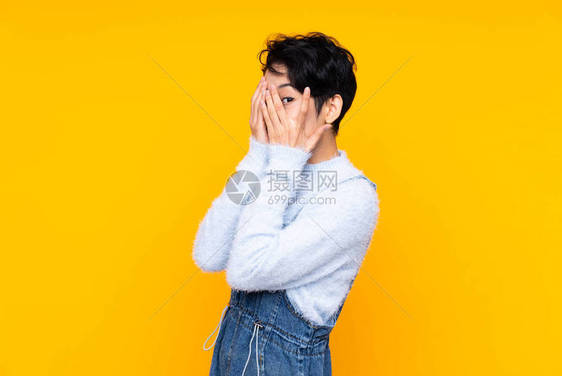 身穿长裤的亚洲年轻女孩在孤立的黄色背景上图片
