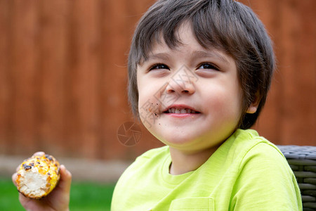 饥饿的小男孩吃烤甜玉米的头像图片