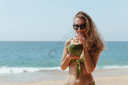 女孩在沙滩上喝椰子图片