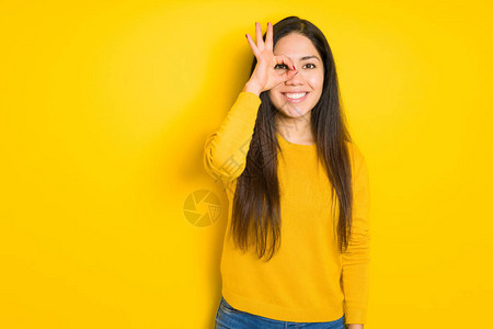 美丽的黑发女人在黄色孤立的背景下做着很好的手势图片