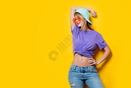 有橙色眼镜和黄色背景帽子的年轻时装女孩图片
