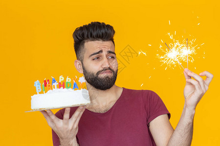 正面的年轻人拿着一个快乐的生日蛋糕和两盏燃烧的灯光图片