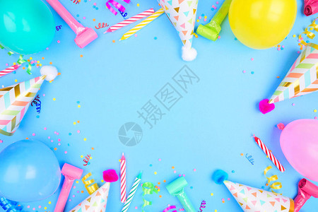 蓝色背景上的生日聚会框架五彩纸屑气球派对帽和彩带的顶视图片