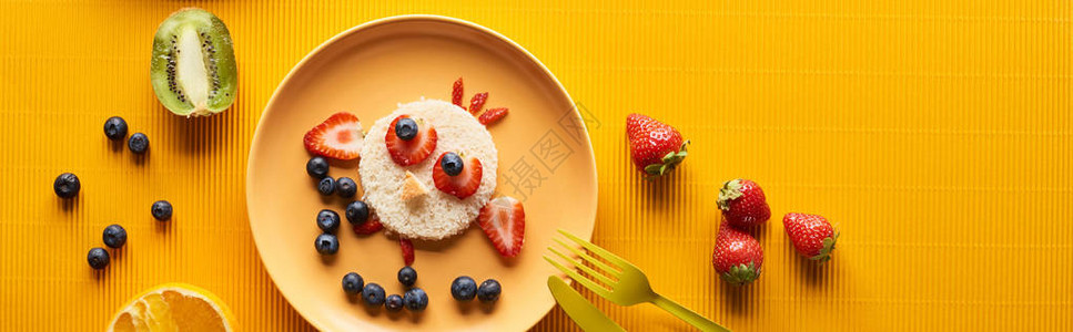 盘子顶部的景色和花美动物由多彩橙色背景的食物制图片