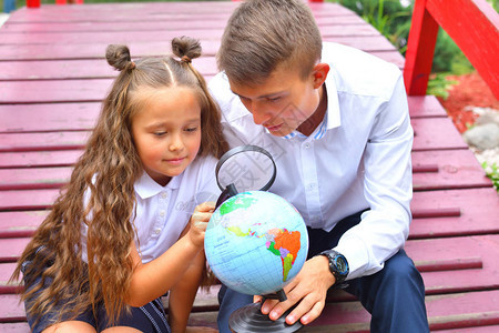男孩和一年级女孩通过放大镜看地球体贴的和女生使用放大镜告别o贝尔知识图片