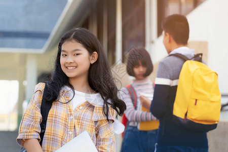 年轻学生少女高中生背着书包拿着笔记本与背景