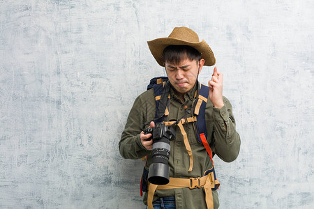 年轻探险家男子拿着相机交叉手指图片