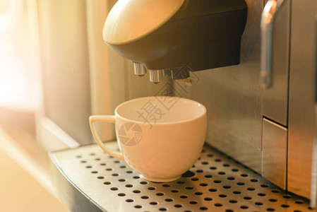 白色杯子站在自动咖啡机冲压板上请使用图片