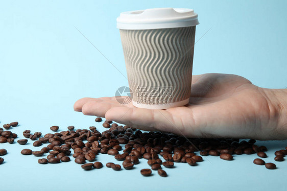 散落的咖啡豆和被手拖住的咖啡杯图片