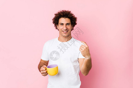 年轻的caucasian卷发男子拿着茶杯用手指着你好像邀图片