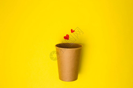 在黄色背景上印有纸心的开放手工艺纸杯平坦创用最小概念复制空间图片