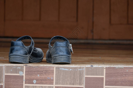 校舍木地板上的学生旧黑色标准鞋在学期接近的图片