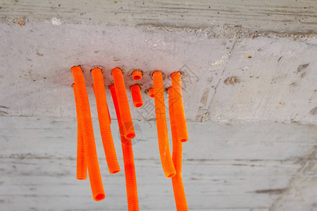 装有橙色保护肋骨塑料软管的电缆从混凝土天图片
