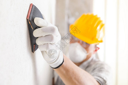 粉碎板或画家在翻修期间将白墙新石膏表面砂成沙子图片