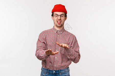 肖像滑稽不情愿的年轻人在红色无檐小便帽和眼镜图片
