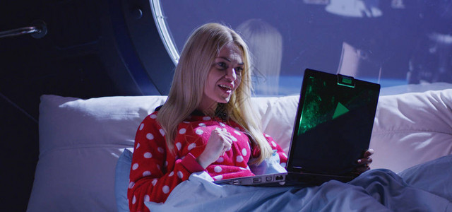 一名年轻妇女坐在一艘航天飞船的床上时使用笔记本图片