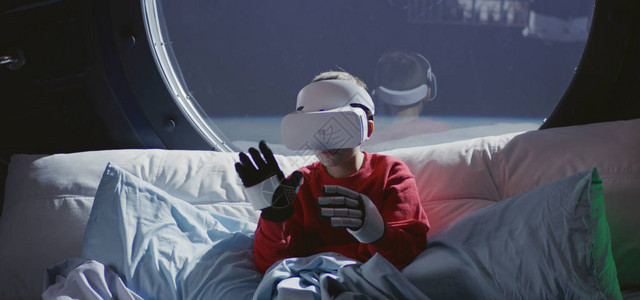 一名男孩在飞船上用VR头盔和图片