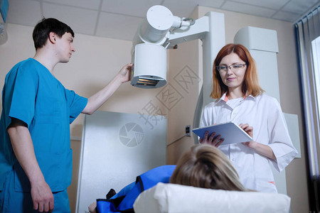 护士和一位放射科医生在医务室的仪器上对病人进行X光检查图片