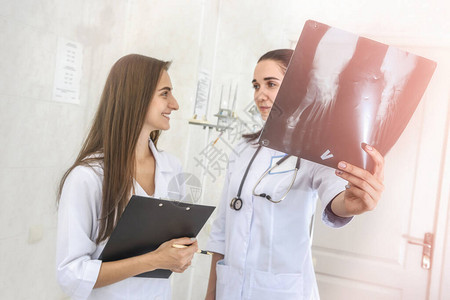 两位年轻医生讨论病人的足部X光片一名医生拿着胶片图片