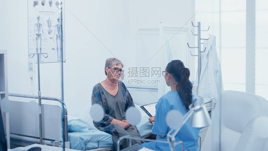 高级女病人在病床上与护士交谈透过玻璃窗拍摄现代医院或私人诊所的医疗保健医疗办公室治疗中的疾高清图片下载-正版图片503699905-摄图网