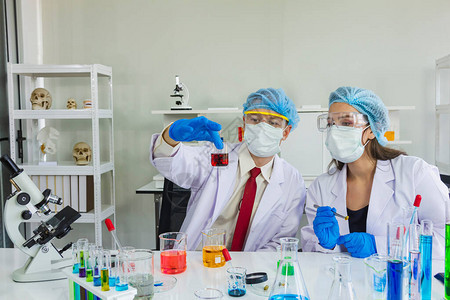 女和男科学家在实验室的烧杯和试管中戴上发网眼镜和面罩图片
