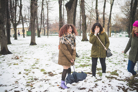 三名年轻妇女在公园中走着雪盖喜乐关图片
