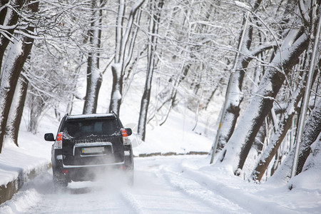 在雪路冬季的大黑色suv车图片