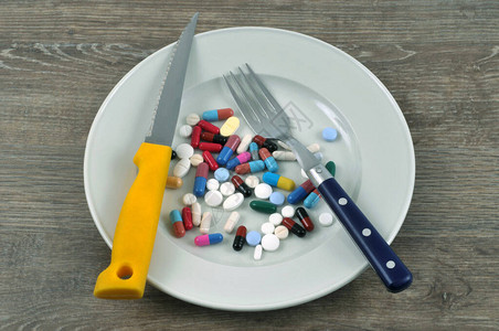 用餐具装满一盘药物的食欲抑制概念图片