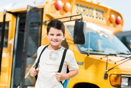 带着背包站在校车前面的男孩笑着图片