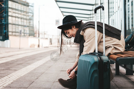 年轻旅游女孩坐在公共交通站系鞋带图片