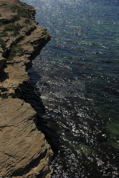 以闪亮的海面为背景的岩石海岸图片