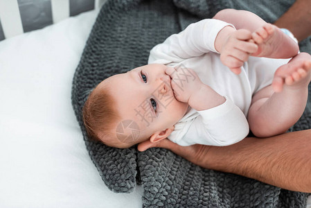 男人抚摸躺在毯子上的婴儿床上的可爱婴儿的剪影图片
