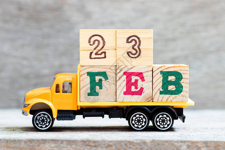 卡车在木材背景上持有第23feb字的母块图片