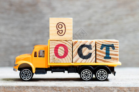 卡车在木材背景上持有9oct字的母块图片